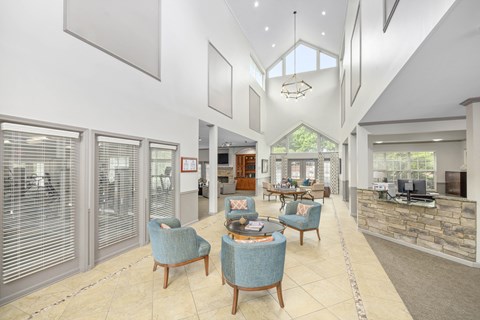 a large living room with blue chairs and a kitchen with windows